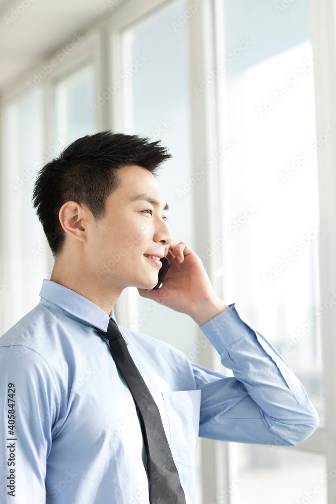 Portrait of young businessman talking on cell phone in office