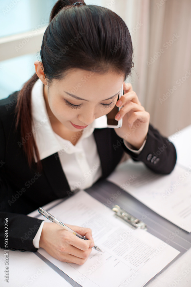 女商人在签署文件时打电话