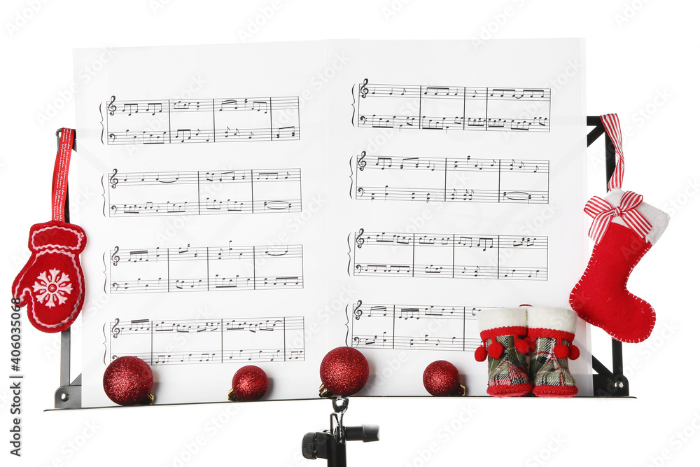 Music sheets with notes and Christmas decor on stand against white background