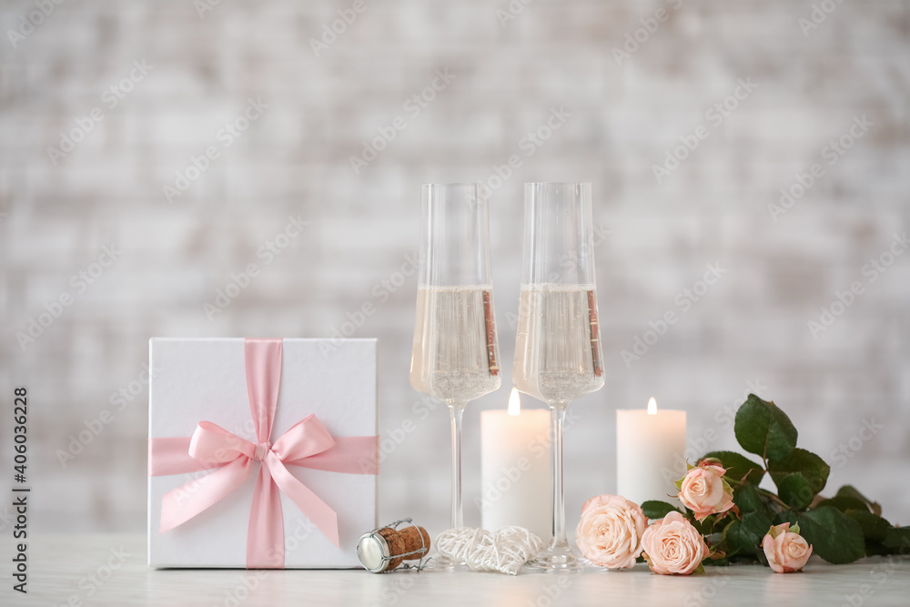 Glasses of champagne, flowers, candles and gift for Valentines Day on table