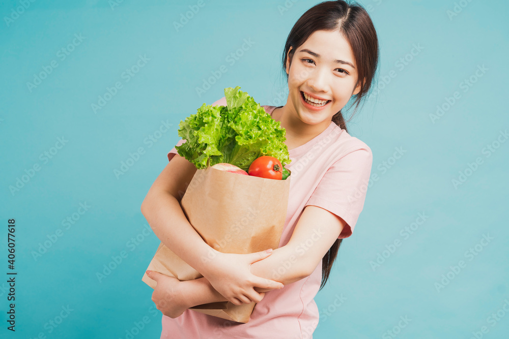 年轻女孩在绿色背景下拿着一袋刚买的蔬菜