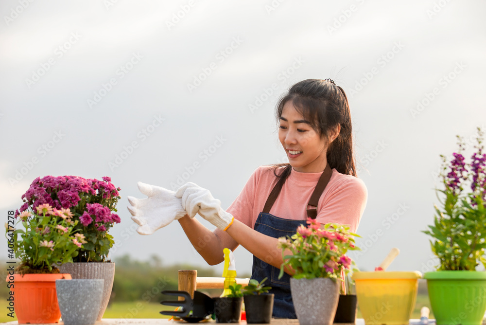 微笑的亚洲年轻女子戴着手套在户外花园种花的肖像