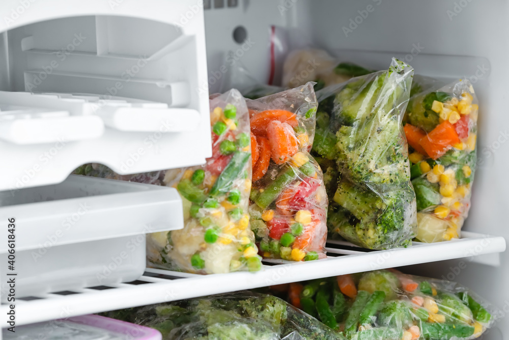 Plastic bags with frozen vegetables in refrigerator