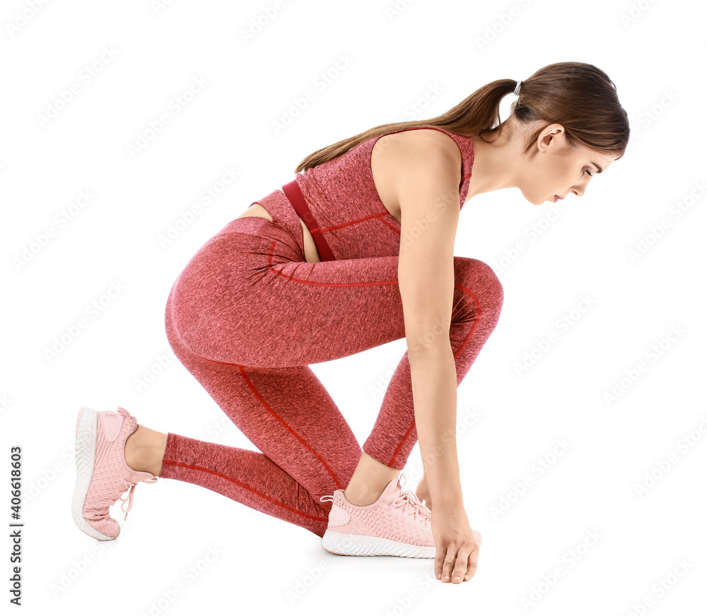 Sporty young woman standing in crouch start position isolated on white background