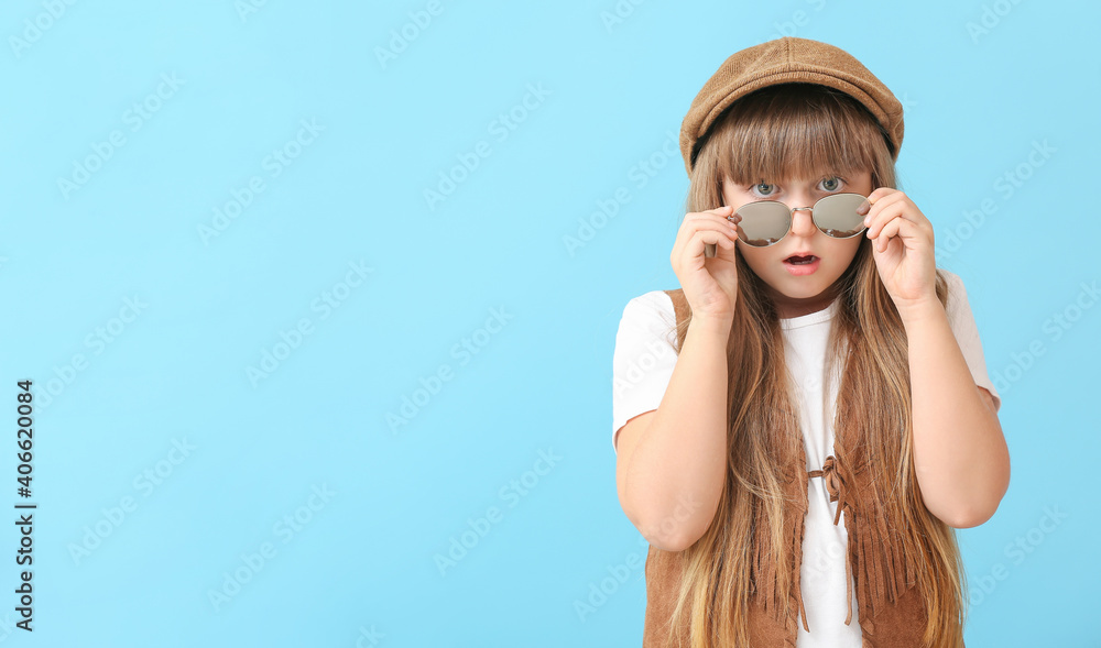 Surprised little girl wearing stylish sunglasses against color background