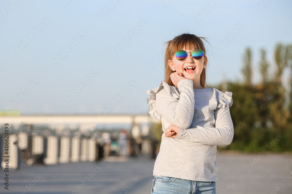 戴着时尚太阳镜的可爱小女孩在户外