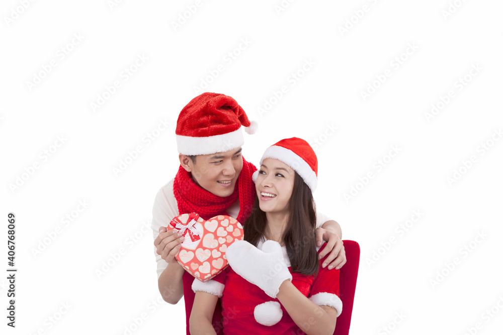 Portrait of young couple wearing Santa hats,holding gift