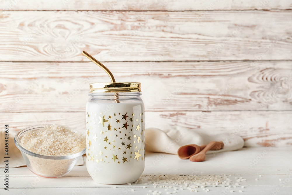 Jar of tasty rice milk on light wooden background