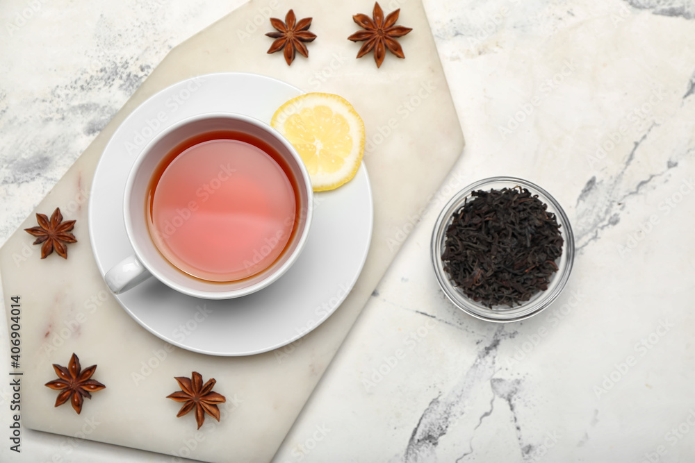 Cup of hot tea and dry leaves on light background