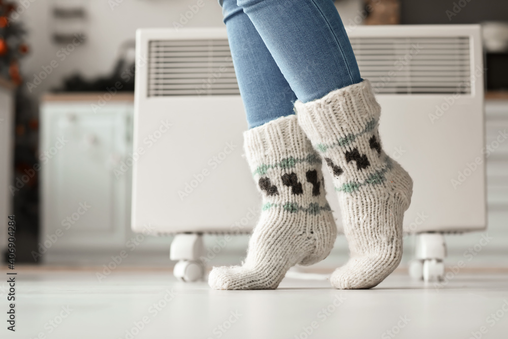 Woman wearing knitted socks at home. Concept of heating season