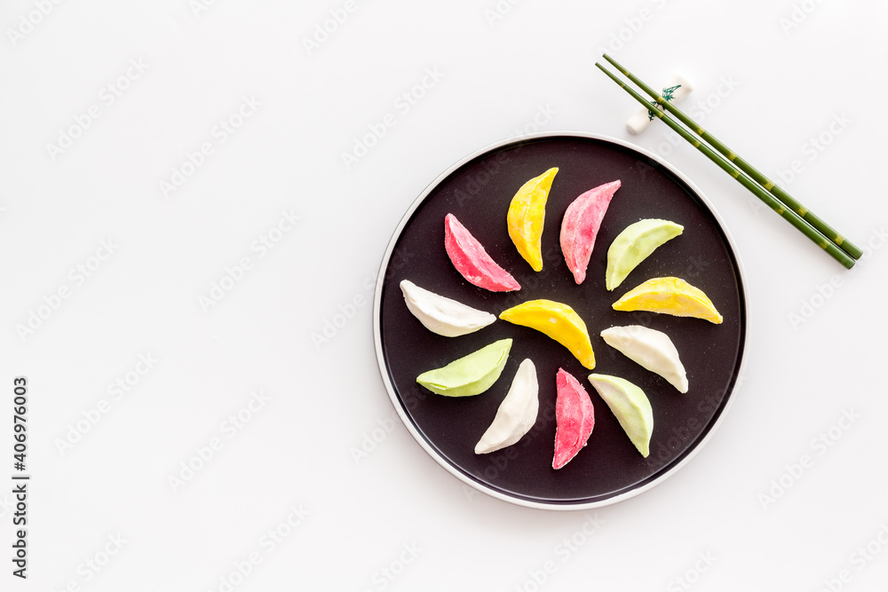 Chinese colourful steamed dumplings on black plate, top view