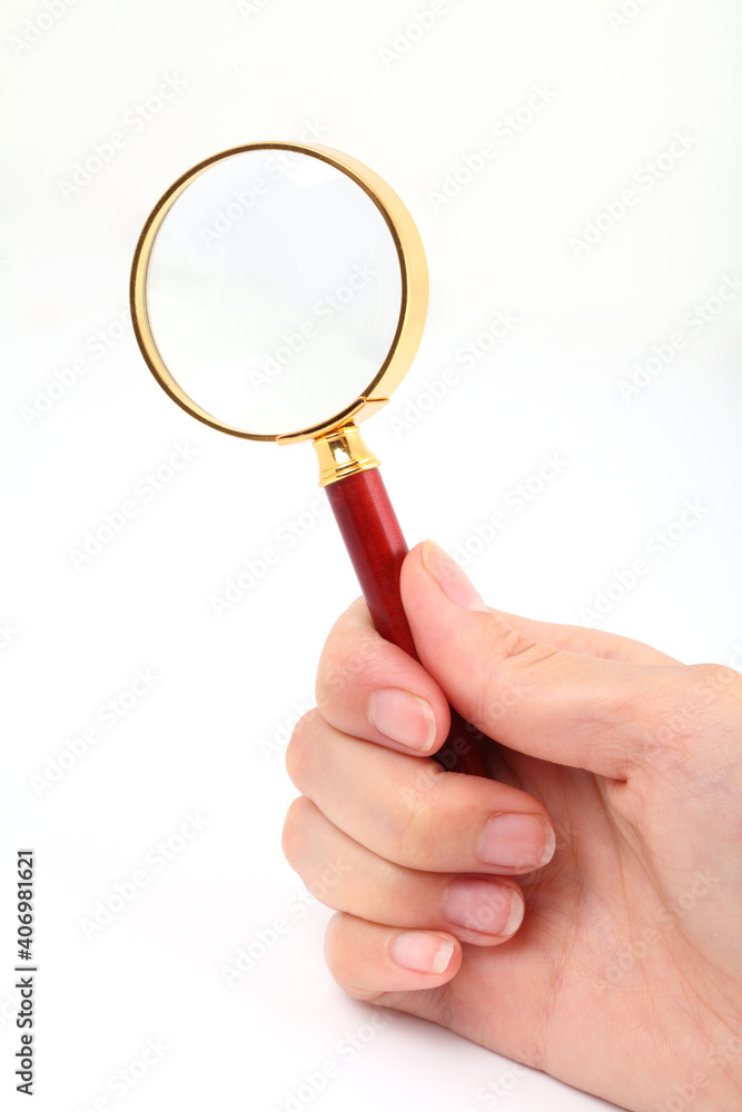 A hand holding a magnifying glass