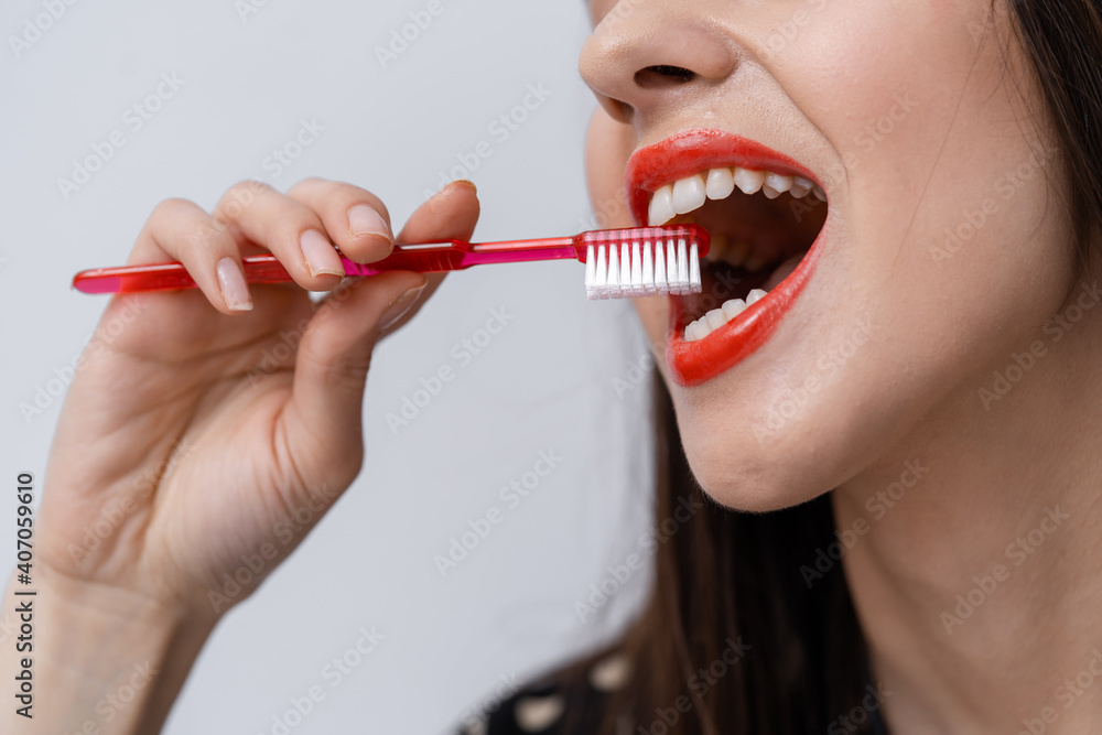 Red toothbrush in hands of a woman with red lips. Healthy teeth concept. Selective focus. Unrecogniz