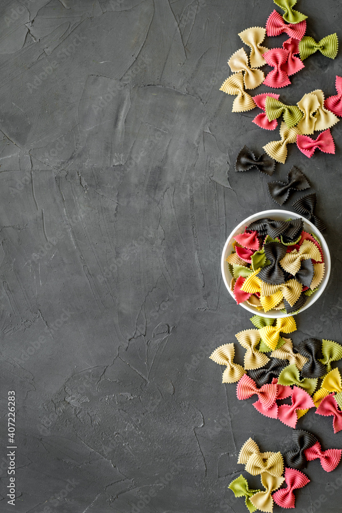 Italian farfalle pasta in bowls. Raw multicolored farfalle pasta, overhead view