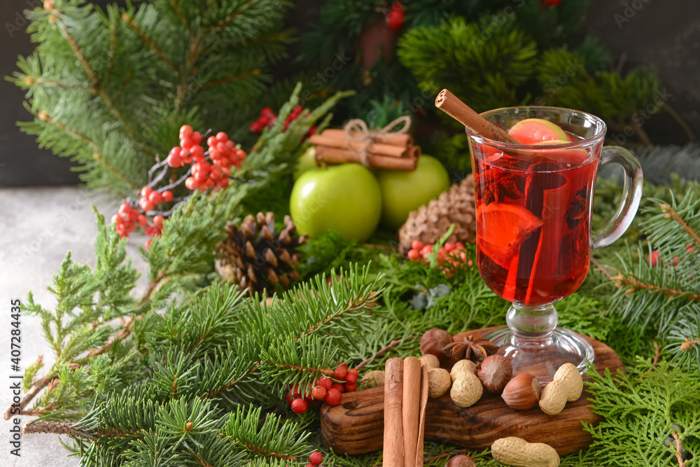 Tasty mulled wine with cinnamon in glass on Christmas tree branches