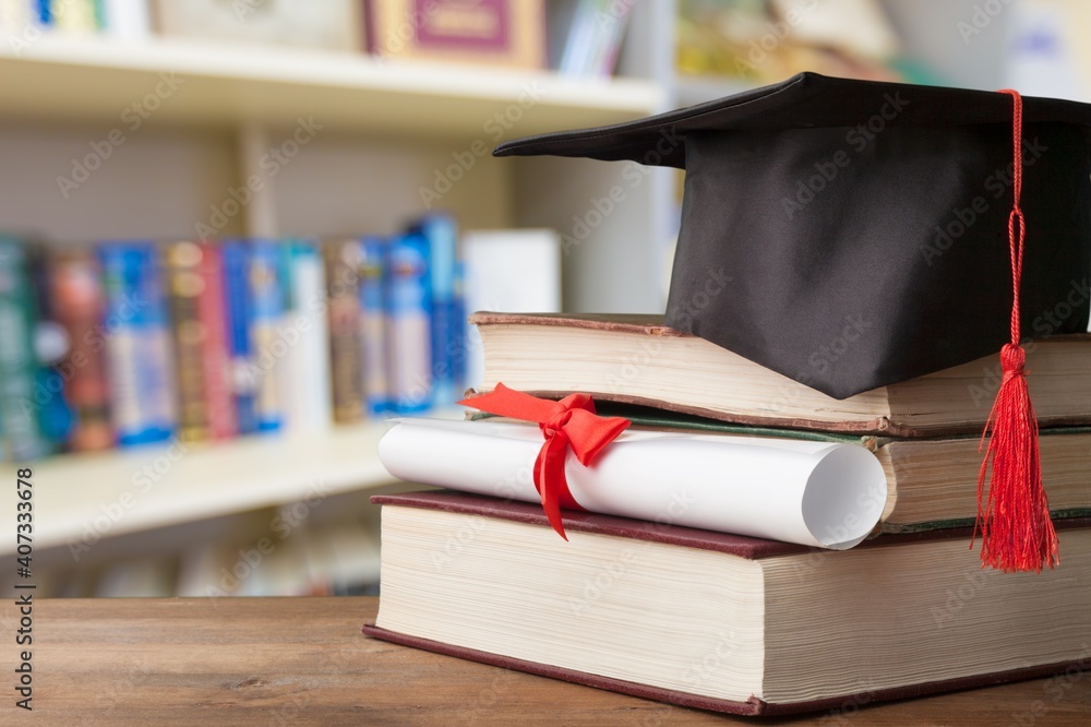 Graduation hat on stack of books and diploma