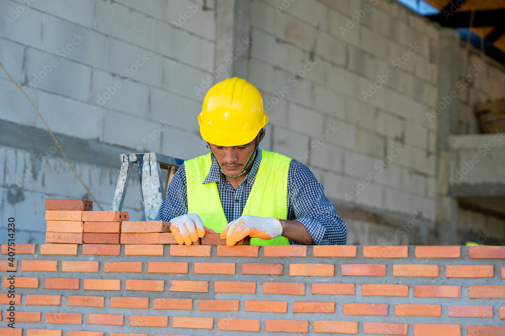 Industrial bricklayer installing bricks on construction site,Bricklayer worker installing brick maso