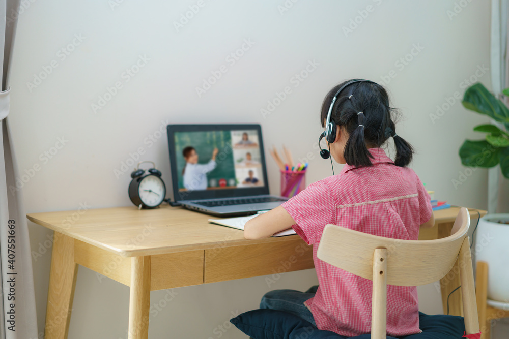 亚洲女学生与老师和同学在客厅的电脑上进行视频会议电子学习