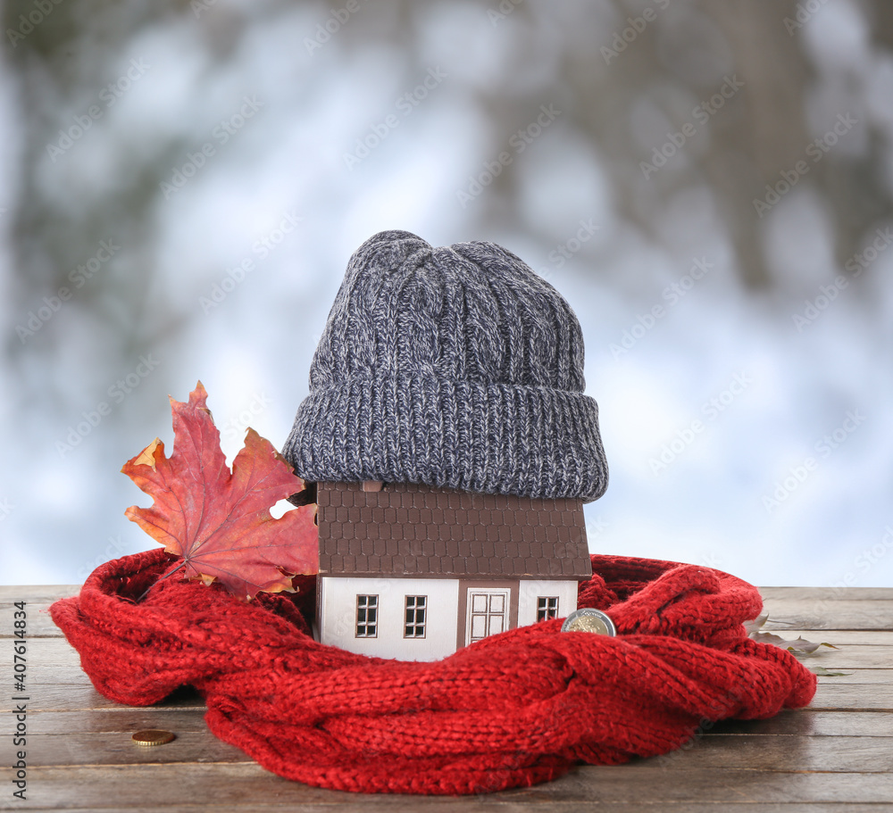 Figure of house and warm clothes on table outdoors. Concept of heating season