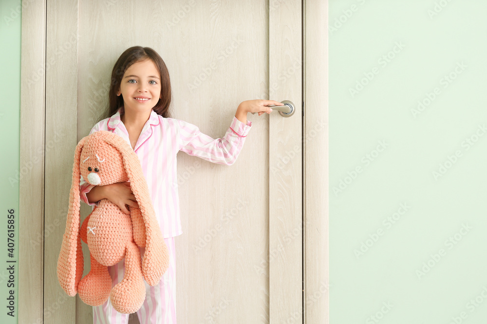 Cute little girl standing near closed door