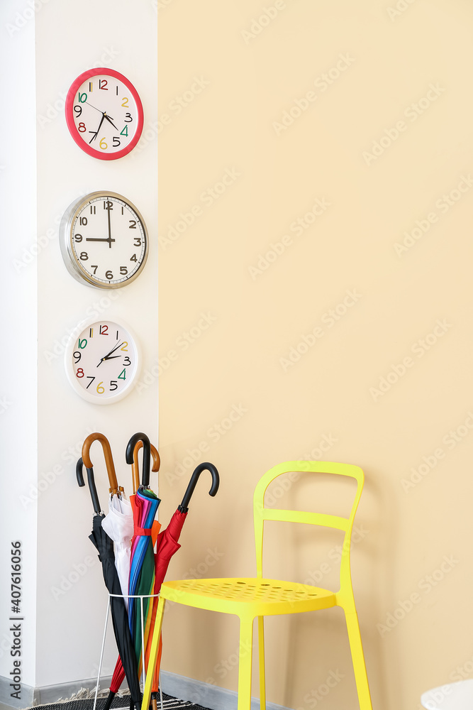 Different clocks hanging on color wall in room