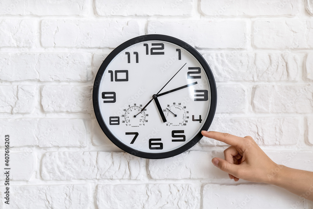 Female hand with clock on brick wall