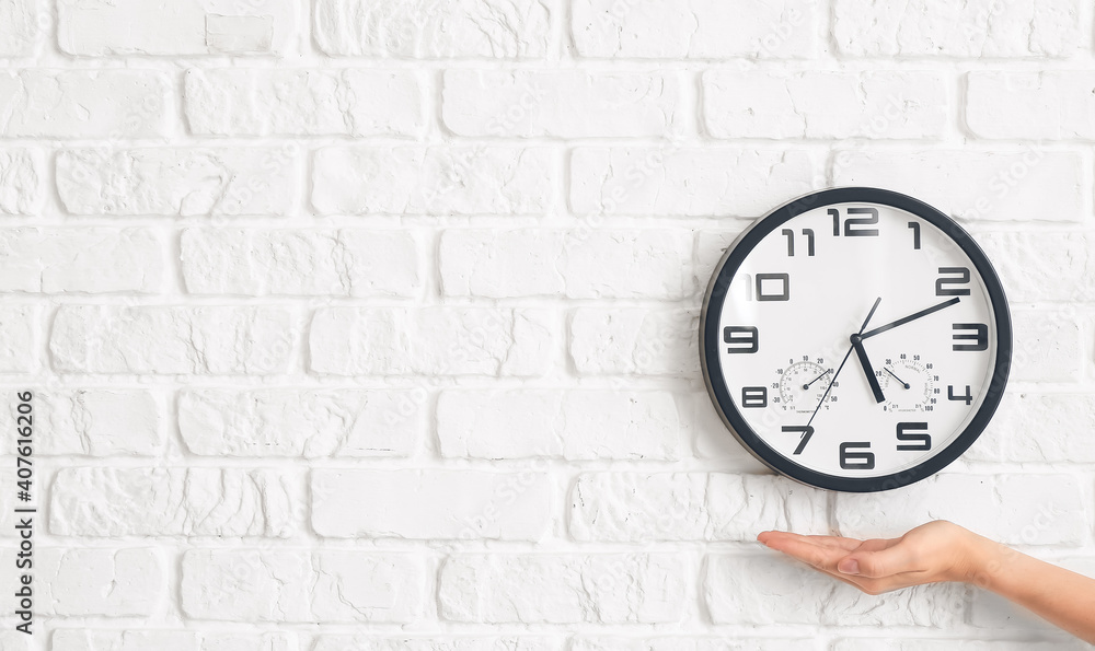 Female hand with clock on brick wall