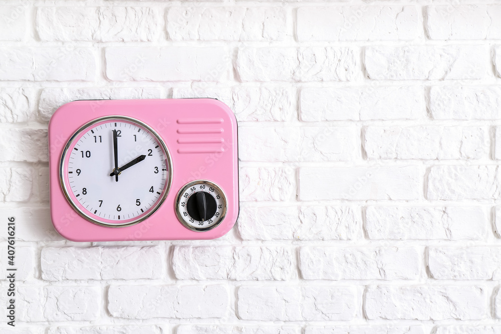 Modern clock hanging on brick wall