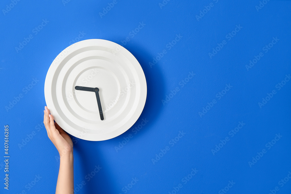 Female hand with clock on color wall