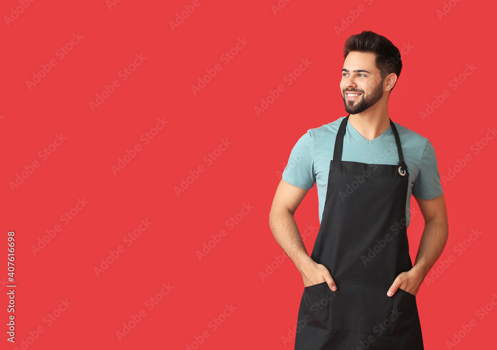 Young man wearing apron on color background