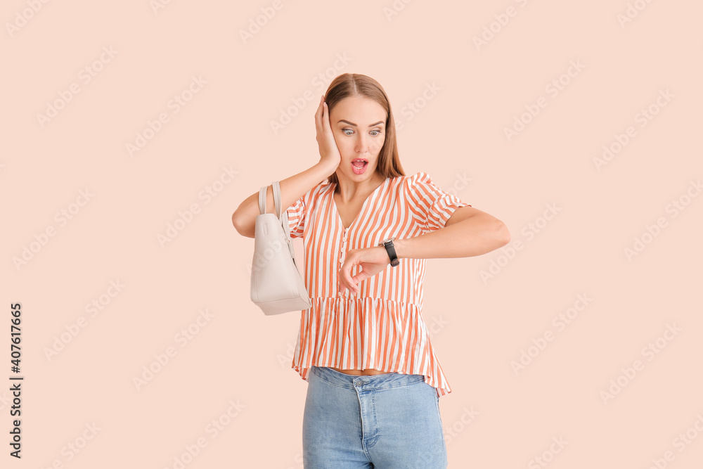 Shocked woman looking at wristwatch on color background