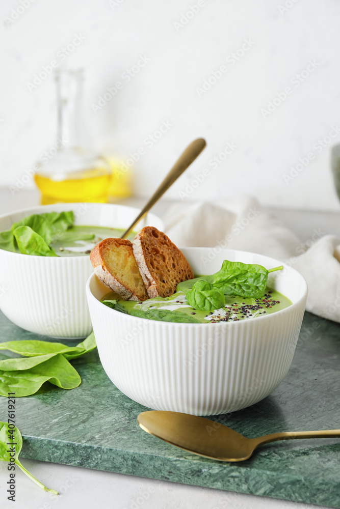 Bowls with tasty spinach soup on table