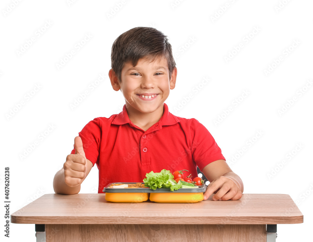 Schoolboy with lunchbox on desk against white background