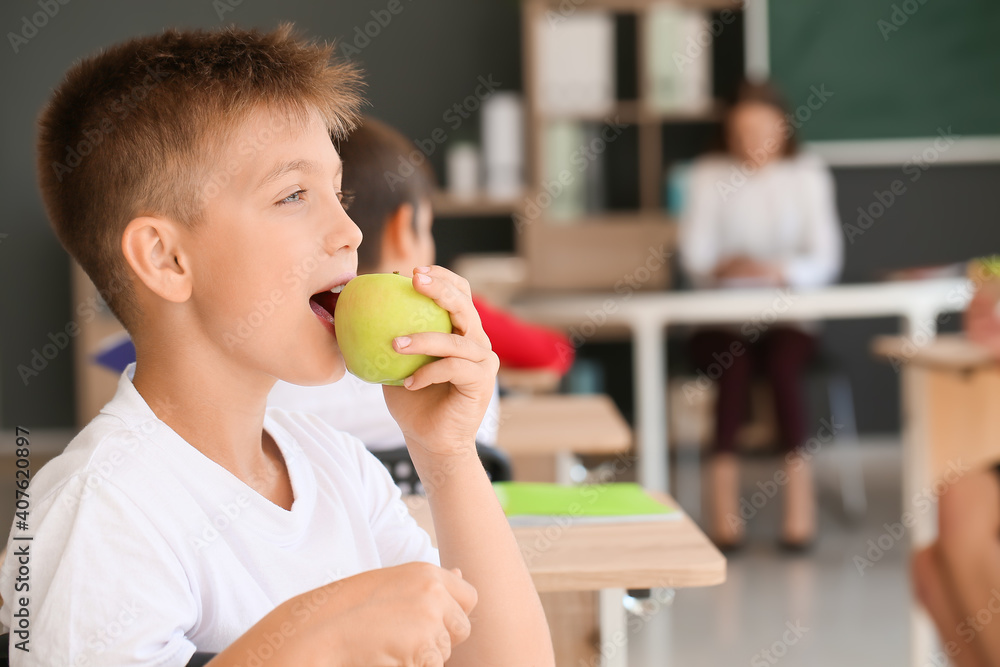 Schoolboy eating apple in classroom