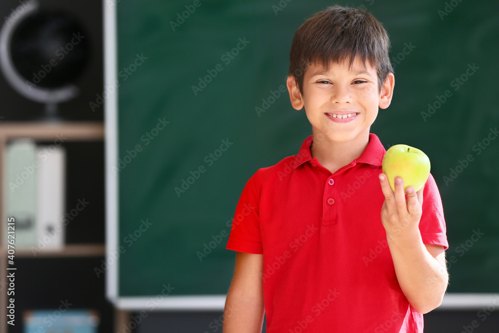 Schoolboy with apple against blurred background in school