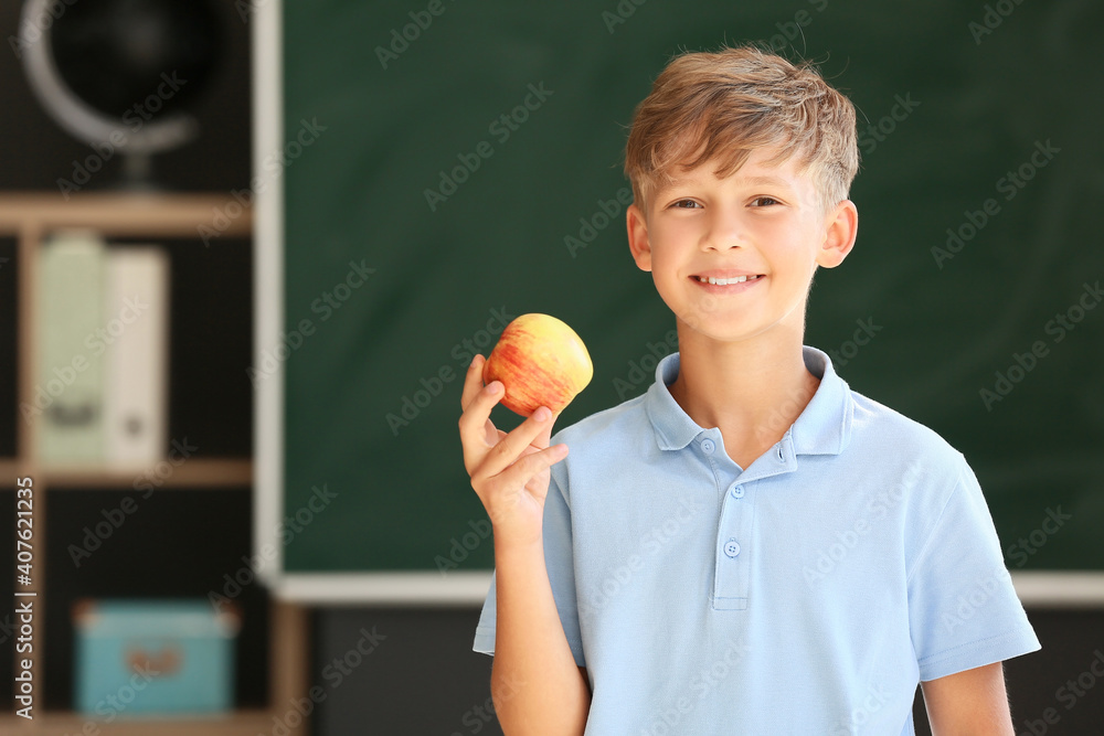 Schoolboy with apple against blurred background in school