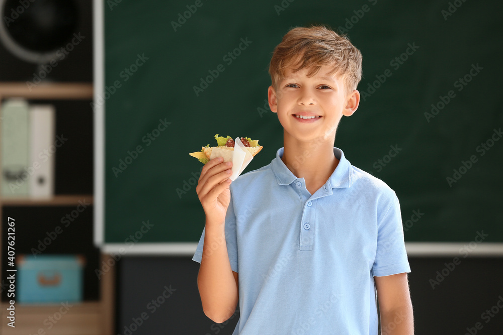 Schoolboy with sandwich against blurred background in school