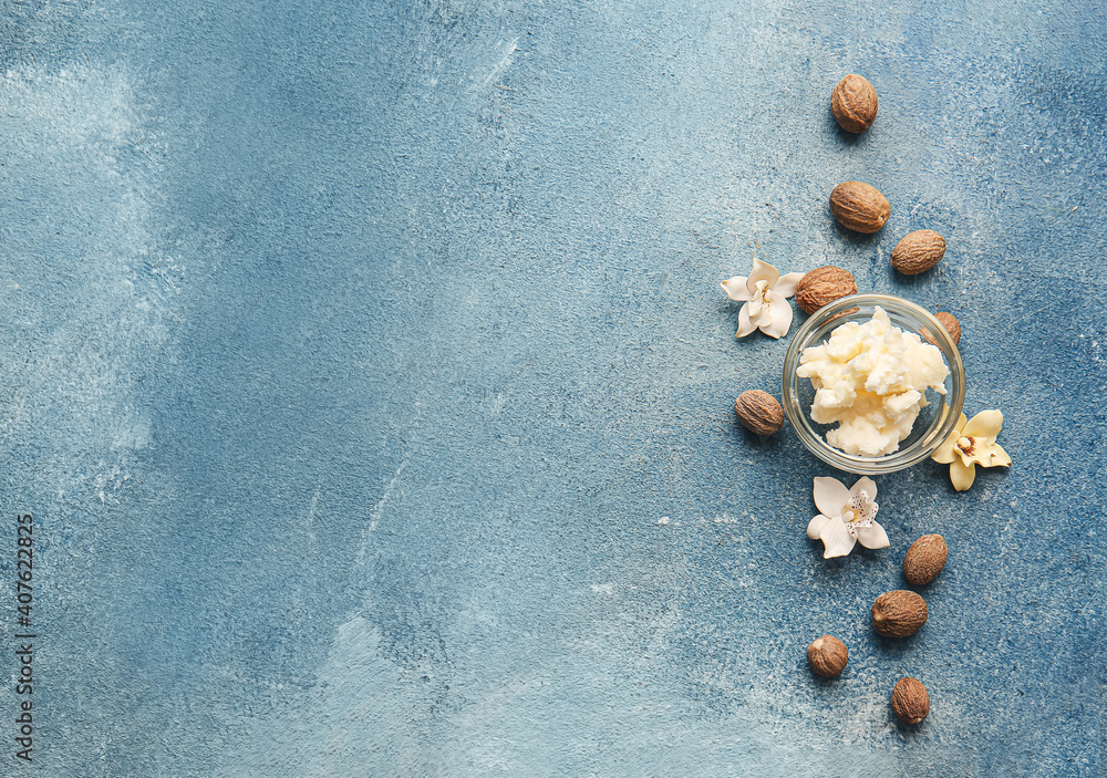 Bowl with shea butter and nuts on color background