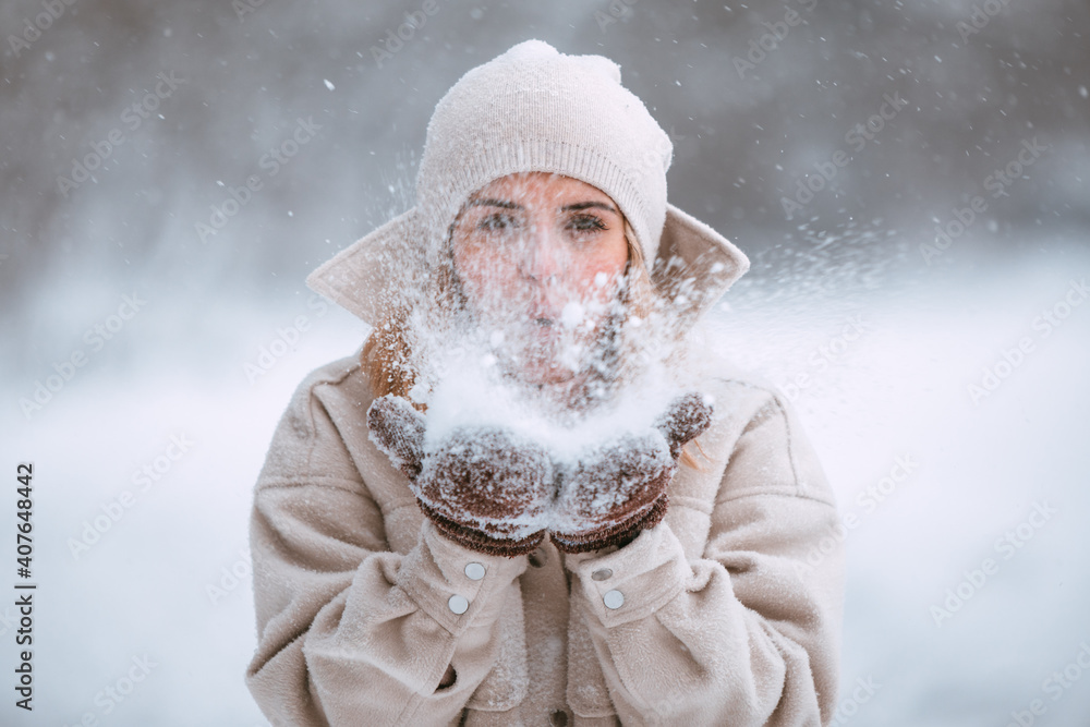 美丽的女人在雪地公园吹雪