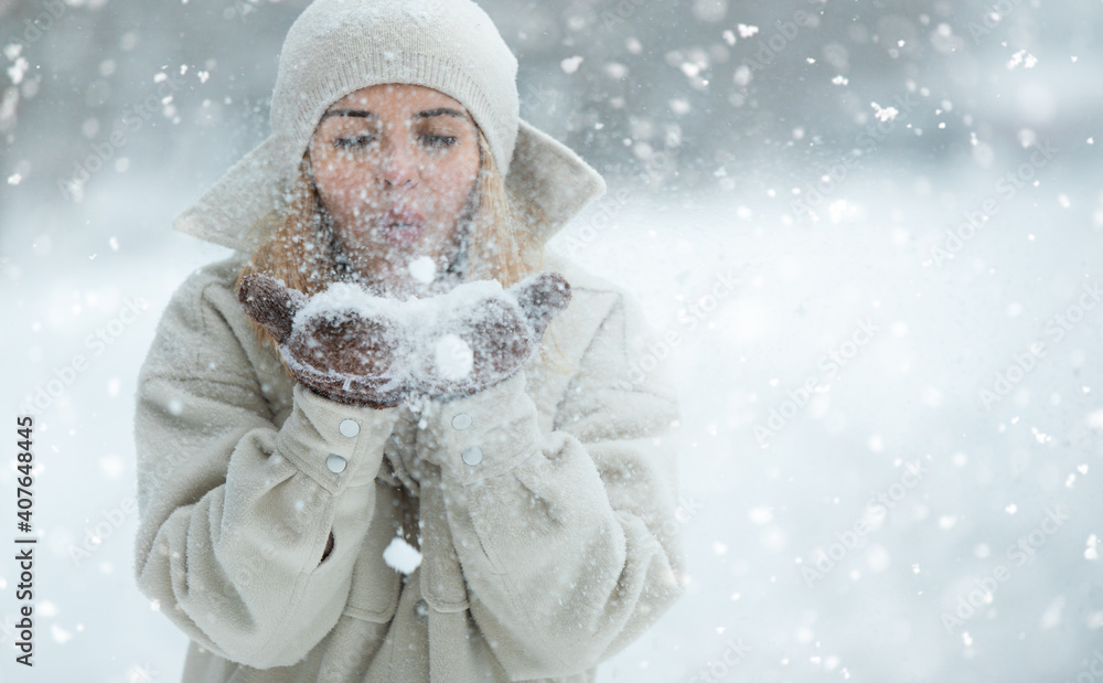 美丽的女人在雪地公园吹雪