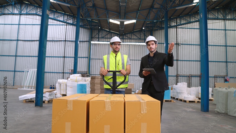 Factory workers deliver boxes package on a pushing trolley in the warehouse . Industry supply chain 