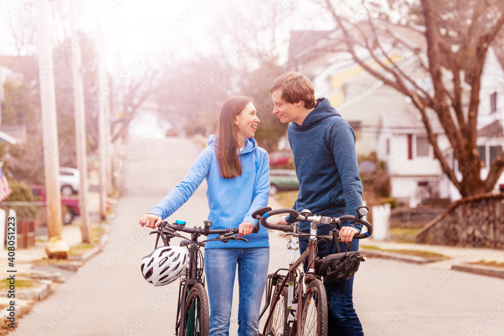 Young couple walk and closely talk holding bikes on the street in USA