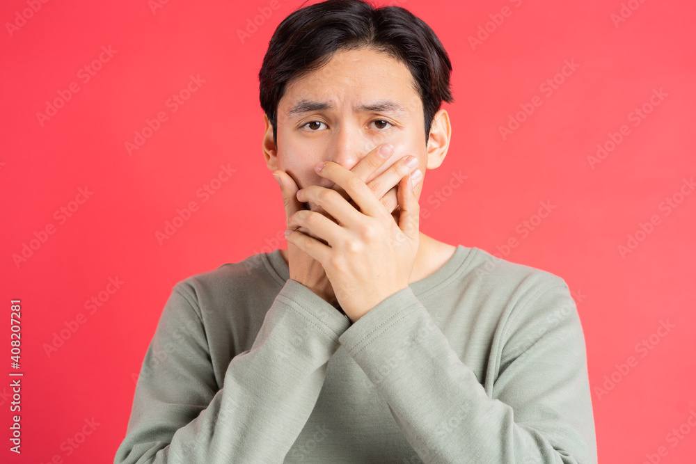 A photo of a handsome Asian man covering his mouth so as not to miss out on someone elses secret