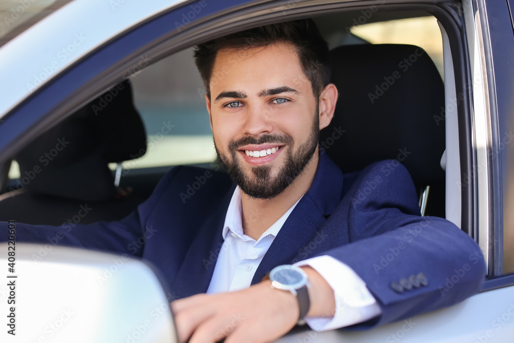 Handsome businessman with stylish wristwatch driving car