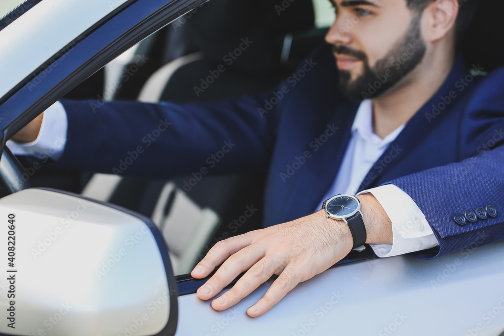 Handsome businessman with stylish wristwatch driving car