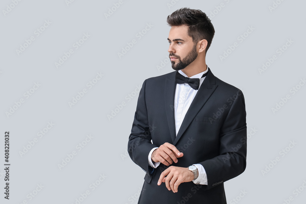 Handsome businessman with stylish wristwatch on light background