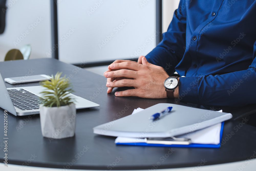 Young businessman with stylish wristwatch working in office