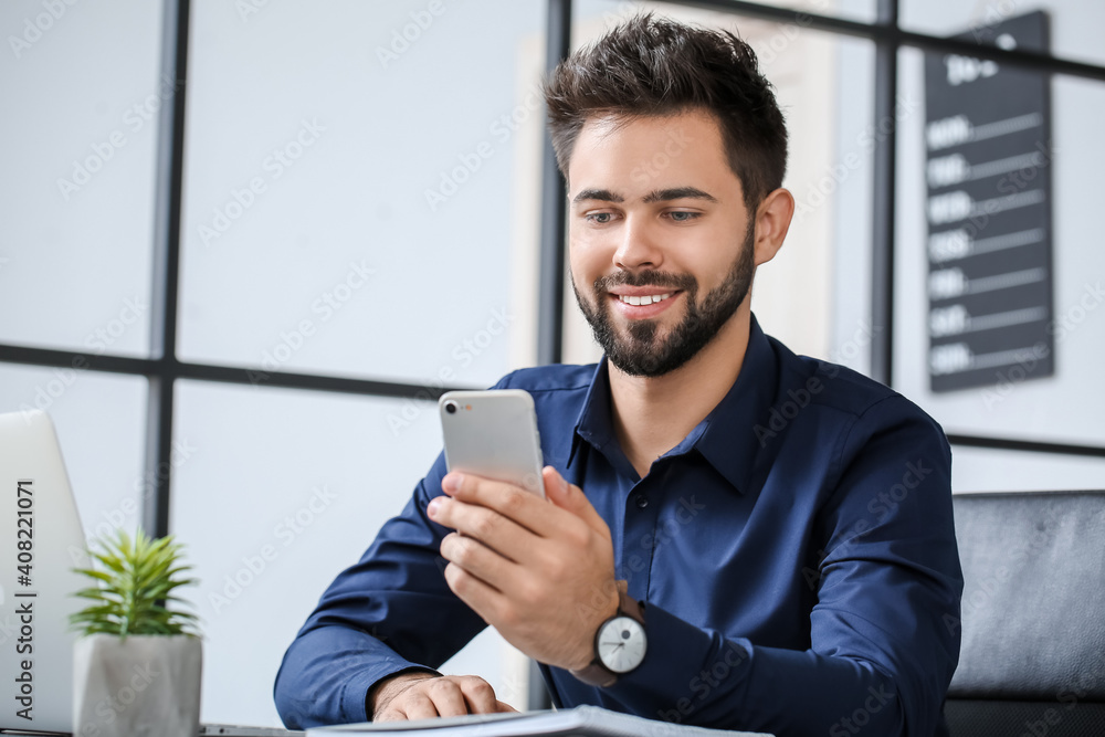 Handsome businessman with stylish wristwatch and mobile phone in office