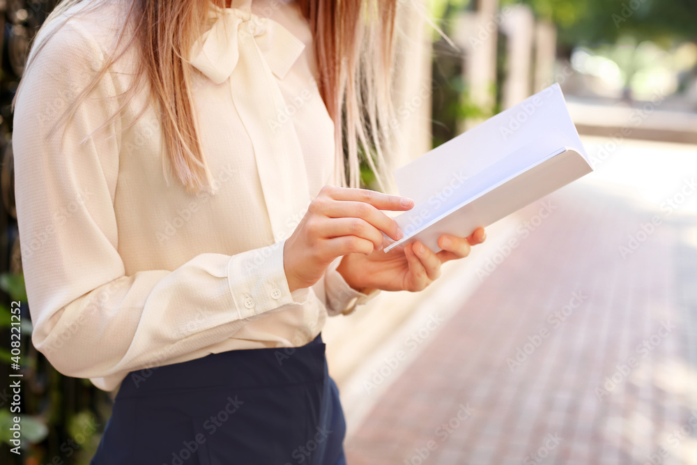 Young woman reading blank book in park