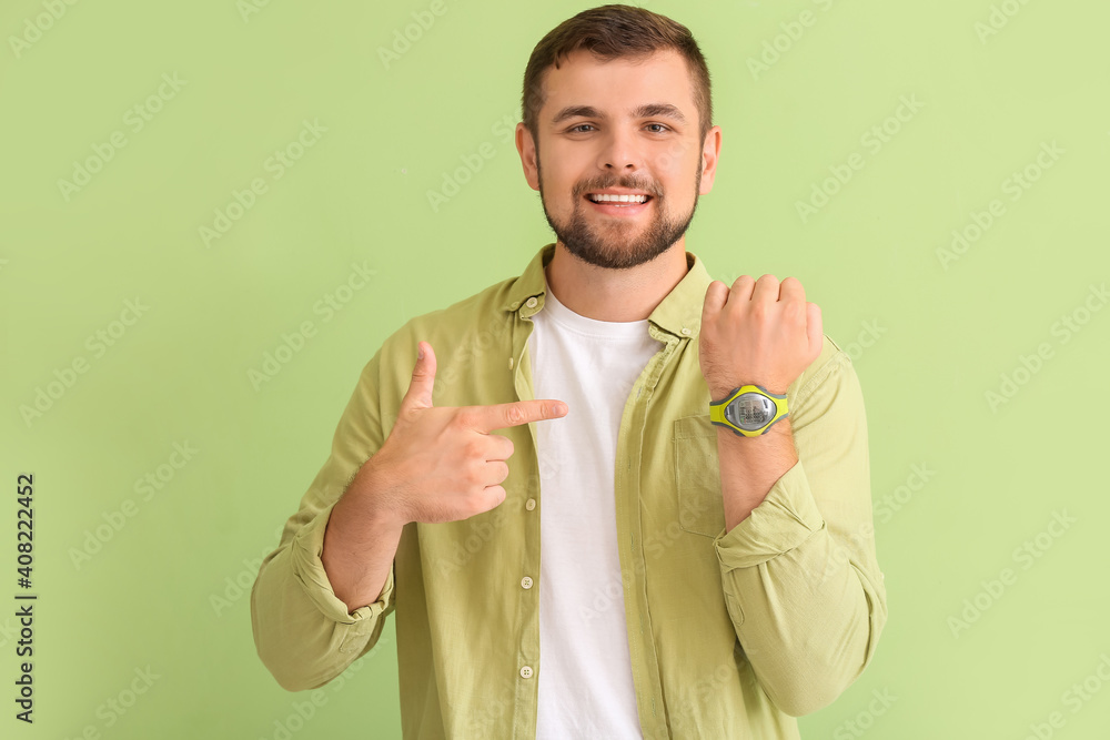 Handsome man with wristwatch on color background
